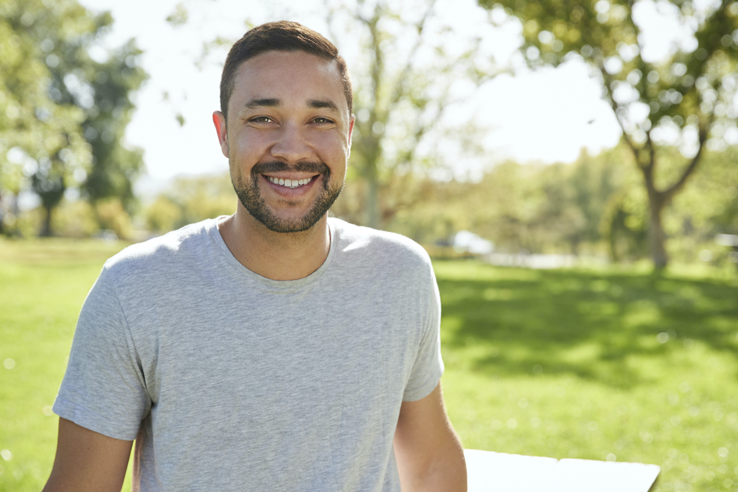 Outdoor Head And Shoulders Portrait Of Smiling Man In Park