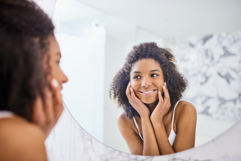 A woman smiles at hersellf in the mirror